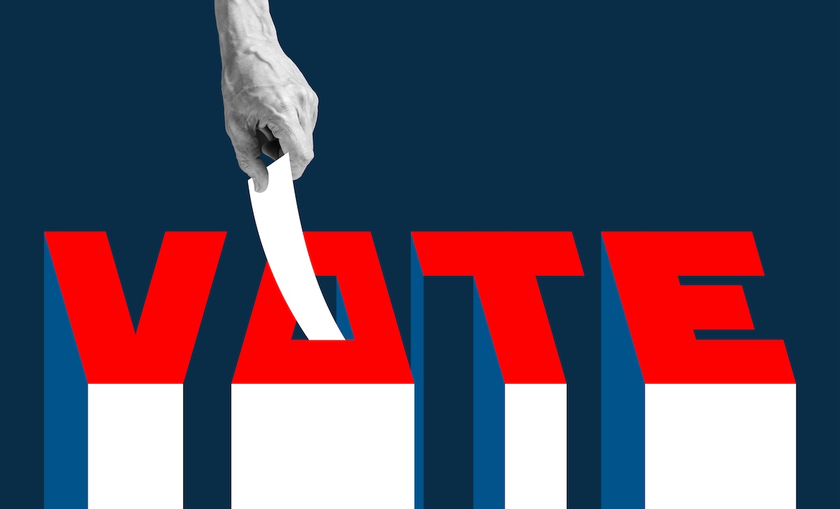 A hand drops a ballot into the letter "O" of the word "VOTE"